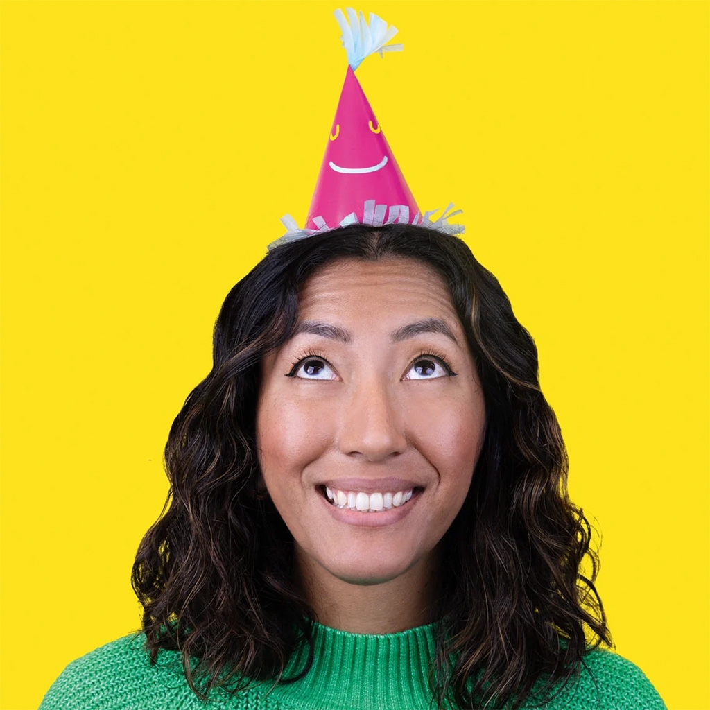 party hat, pink hat, lächelnde person, grüner pullover, gelber Hintergrund