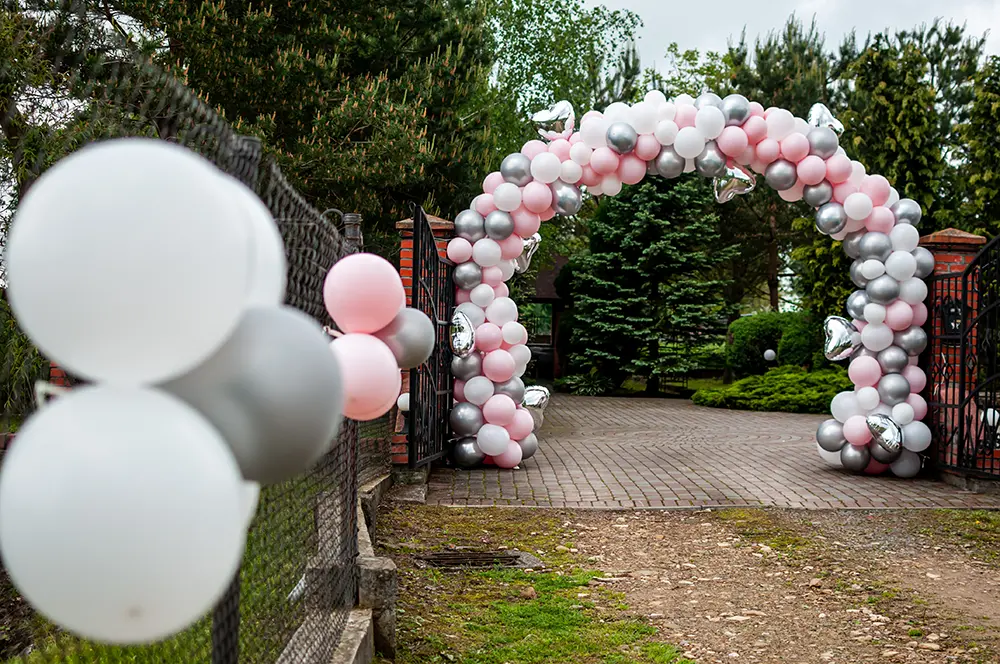 Ballonbogen in Rosa, Weiß und Silber an einem Garteneingang