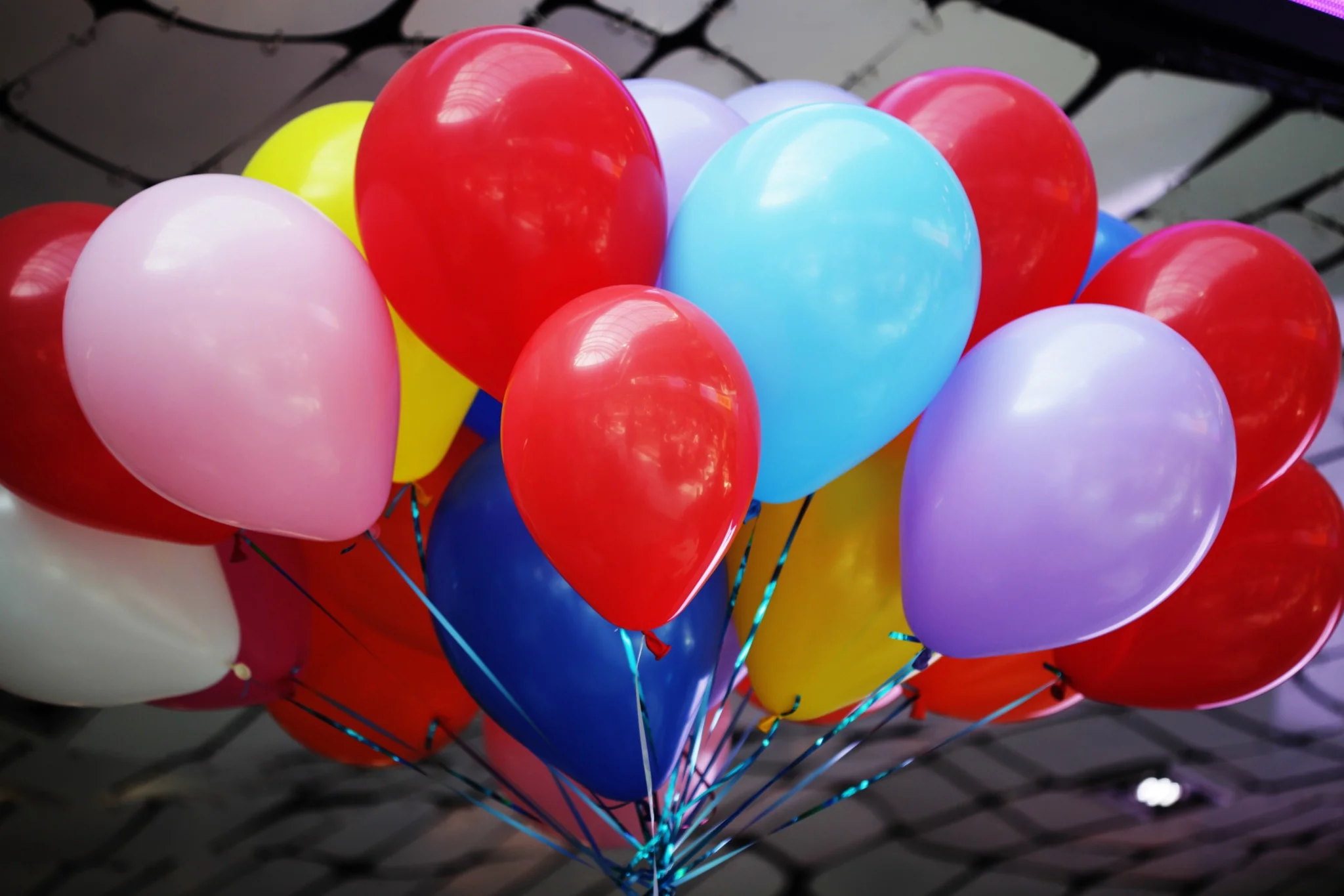 Bunter Strauß aus schwebenden Latexballons mit zusammengebundenen Bändern